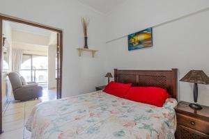 a bedroom with a bed with red pillows and a chair at Cabanas Del Mar 76 By Evermore in Kingsborough +25 photos