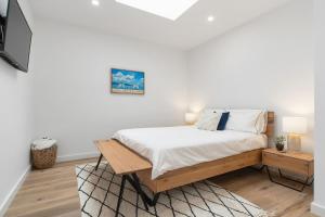 a white bedroom with a bed and a tv at Beachfront Bliss Luxury Views in Rye