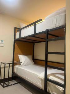 a bedroom with two bunk beds with white sheets at EAIN-WORKplusSTAY in Bangkok