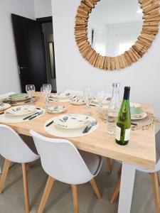 a wooden table with white chairs and a bottle of wine at Atico playa de Miramar in Miramar