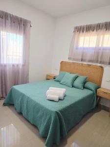 a bedroom with a green bed with two towels on it at Atico playa de Miramar in Miramar +5 photos