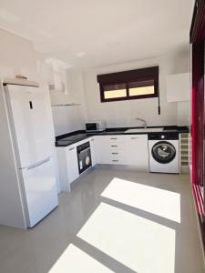 a white kitchen with a refrigerator and a dishwasher at Atico playa de Miramar in Miramar