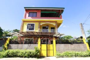 a yellow and pink house with a balcony at Joval Homestay in Coron