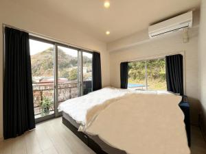 a bedroom with a bed and a large window at ゲストハウス&café chiuwo in Kawazu