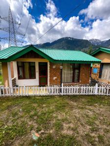 a small house with a green roof at Aura Montane luxury cottages in Manāli