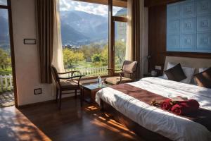 a bedroom with a bed and a large window at Aura Montane luxury cottages in Manāli