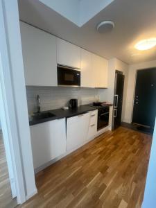 a kitchen with white cabinets and a wooden floor at Nice flat in Barkarby in Järfälla +7 photos