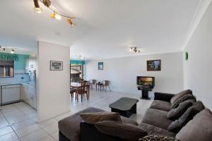 a living room with a couch and a table and a kitchen at Pelican Place in The Entrance