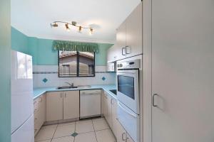 a kitchen with white cabinets and blue walls at Pelican Place in The Entrance +1 photo