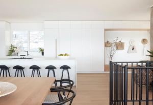 a kitchen with white cabinets and a wooden table with stools at The Palms in Palm Beach