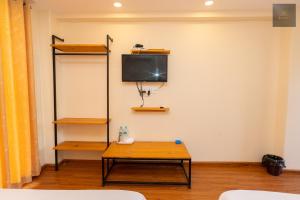 a room with a table and a tv on a wall at Hotel Kaavi in Pokhara