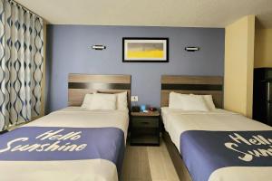 two beds in a hotel room with blue walls at Days Inn by Wyndham Freeport in Freeport +60 photos