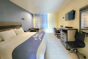 a hotel room with a bed and a desk at Days Inn by Wyndham Freeport in Freeport