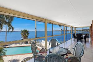 a balcony with a table and chairs and a view of the ocean at Toukley Waterfront House in Toukley