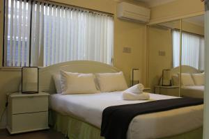 a bedroom with a large white bed with a mirror at Toukley Waterfront House in Toukley +12 photos
