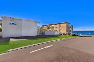 a building on the side of a road next to the ocean at The Sands Apartment 6 in The Entrance