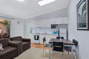 a kitchen and living room with a table and chairs at Surfside Palms 14 in The Entrance