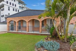 a brick house with a balcony and palm trees at Surfside Palms 14 in The Entrance