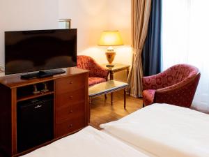 a hotel room with a bed and a flat screen tv at DORMERO Hotel Halle in Halle an der Saale