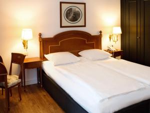 a bedroom with a large white bed and a desk at DORMERO Hotel Halle in Halle an der Saale