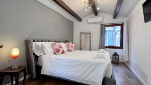 ein Schlafzimmer mit einem Bett mit weißen Laken und rosa Kissen in der Unterkunft Ca' ai Sospiri in Venedig