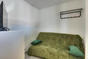a living room with a green couch with two pillows at Appartement Santocha in Capbreton