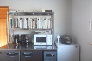 eine Mikrowelle und ein Regal mit Büchern und einer Mikrowelle in der Unterkunft rento in Sobetsu + 11 Fotos