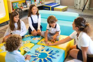 a group of children sitting on the floor playing a game at Hôtel Barrière Le Gray d'Albion in Cannes