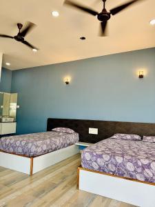 two beds in a room with a ceiling fan at Suites by the Glaswater in Kalyānpur