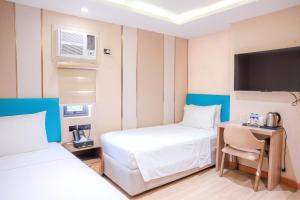 a room with two beds and a desk and a tv at Sunday Belajandro Hotel in Angeles
