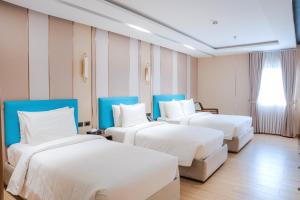 a hotel room with three beds and a window at Sunday Belajandro Hotel in Angeles