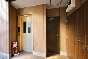 a hallway with a door and a brick wall at Kyo-wa Hotel Oshiage in Tokyo