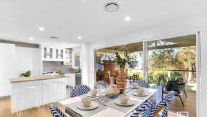 a kitchen and dining room with a table and chairs at Natuna Lakeside Retreat in Budgewoi