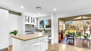 a kitchen with white cabinets and a large window at Natuna Lakeside Retreat in Budgewoi