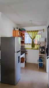a kitchen with a stainless steel refrigerator and a window at La Casita Puerto Arista in Puerto Arista