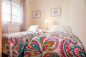 ein Schlafzimmer mit einem Bett mit einer bunten Bettdecke in der Unterkunft Precioso Apartamento la Marina in Rincón de la Victoria