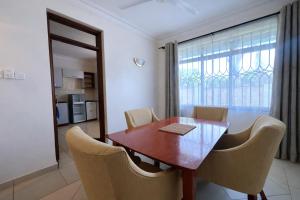 a dining room with a wooden table and chairs at Ary Homestay Nyali At Shikara Apartments 5th Avenue Nyali, Mombasa, Kenya in Mombasa