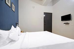 a bedroom with a white bed with a tv on the wall at Open Hotel by Olive - Sadha Siva Airport Road, Chennai in Chennai +18 photos