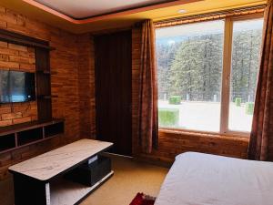a room with a bed and a large window at JB Hotel and Resort in Lohaghāt