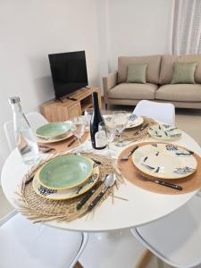 a white dining room table with plates and wine glasses at Apartamento playa de Miramar in Miramar