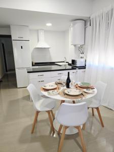 a white kitchen with a table and white chairs at Apartamento playa de Miramar in Miramar +2 photos