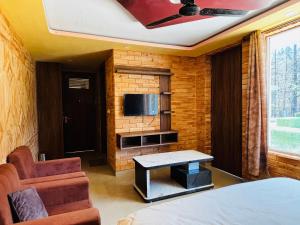 a room with a bed and a table and a tv at JB Hotel and Resort in Lohaghāt +26 photos