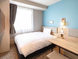 a bedroom with a bed with a desk and a window at Comfort Hotel Takamatsu in Takamatsu