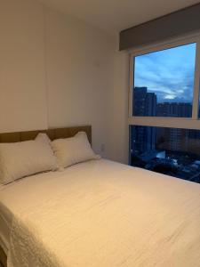 a bed in a room with a large window at Apartamento Novo Infinity in Vila Velha