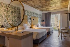 a hotel room with two beds and a mirror at Faranda Collection Barranquilla, a member of Radisson Individuals in Barranquilla