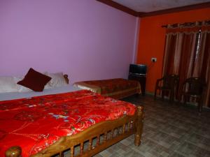 a bedroom with two beds and a red bedspread at Green Villa in Virajpet
