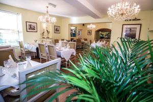a restaurant with white tables and chairs and chandeliers at The Peacock Townhouse Hotel Kenilworth - Warwick in Kenilworth