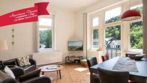 a living room with a table and chairs and windows at Haus Alleegarten in Bad Bertrich