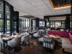 a restaurant with tables and chairs and windows at Grand Mercure Batam Centre in Batam Center