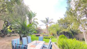 a table and chairs in a garden with trees at Villa Via Hotel Midrand in Midrand